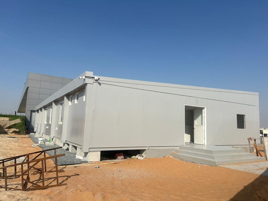 Large prefabricated building with multiple rooms installed on a sandy site in the UAE